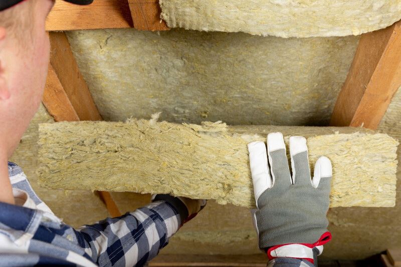 pest control technician inspecting attic insultation for signs of pests